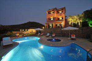 a swimming pool in front of a house at night at Villa Mare e Monti in Almiros Beach
