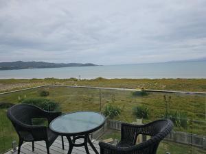 a balcony with a table and chairs and the ocean at Pyramid beach house in Karikari Peninsula