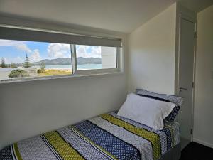 a small bedroom with a bed and a window at Pyramid beach house in Karikari Peninsula
