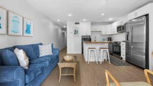 Beachside Condo 13 في شاطئ سانتا روزا: غرفة معيشة مع أريكة زرقاء ومطبخ