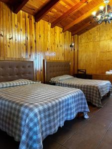 two beds in a room with wooden walls at Departamento en Mazamitla in Mazamitla