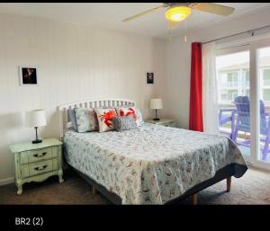 a bedroom with a bed and two tables and a window at Thats What Sea Said in Holden Beach
