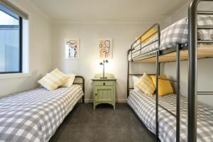 two bunk beds in a small room with a night stand and a table at Two bedrooms family house in Coles Bay with direct access to the Swan River! in Coles Bay
