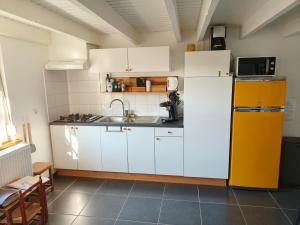 a kitchen with white cabinets and a yellow refrigerator at Le petit blanc in De Haan