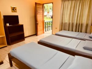 two beds in a room with a television and a door at Villa Paraiso Resort & Waterpark in Camiguin