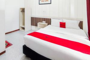 a bedroom with a large white bed with a red blanket at RedDoorz Syariah at Penginapan Eby Padang in Duku