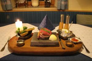 uma bandeja de madeira com comida numa mesa com uma vela em Erlebnislandgasthof Hotel Neiderhell em Kleinholzhausen