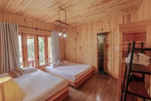a bedroom with two beds in a room with wooden walls at Khai Quynh Villa 3 - Venuestay in Khu Chi Lăng