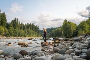 a woman standing on rocks in a river at PNW River Cabin in Darrington