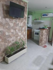 a kitchen with a flat screen tv on a stone wall at Los girasoles in Tandil