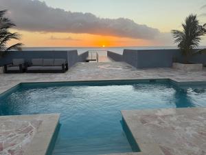 a swimming pool with a sunset in the background at The Cave Beach House in Lagun