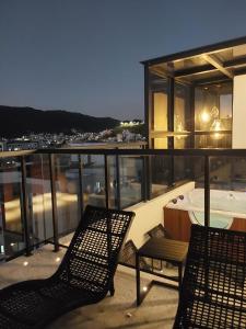 a balcony with two chairs and a tub on a building at Charmoso, moderno e central! 11 in Poços de Caldas