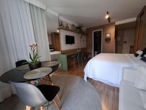 a hotel room with a bed and a table and chairs at Charmoso, moderno e central! 11 in Poços de Caldas