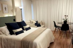 a bedroom with a bed and a table and a couch at Charmoso, moderno e central! 11 in Poços de Caldas +32 photos
