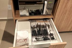 a drawer full of kitchen utensils in a microwave at Charmoso, moderno e central! 11 in Poços de Caldas