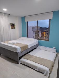 two beds in a room with a large window at Espectacular Apto a 5 minutos del parque del café in Montenegro