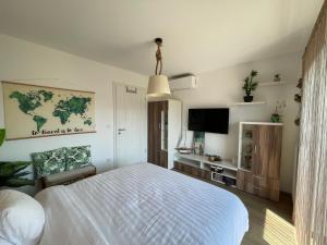 a bedroom with a white bed and a tv at Beachside Apartment in Szántód