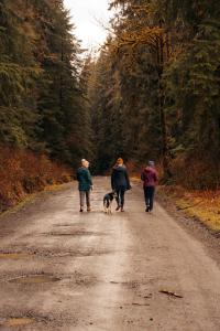 three people walking a dog down a dirt road at Stilly River Haus - Hot tub - Firepit - Fireplace in Granite Falls