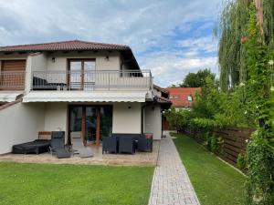 a house with a balcony and chairs in the yard at Beachside Apartment in Szántód