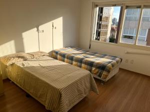 two beds in a room with a window at Apartamento p 10 com 3 quartos e 2 banheiros in Porto Alegre