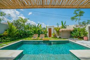 een zwembad met twee stoelen en een huis bij Sun Garden Villa - 2BR Villa in Kerobokan in Kerobokan