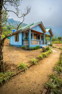 a blue house in the middle of a dirt road at Monratino The Orange Farmstay - Darjeeling in Takdāh