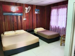 two beds in a room with wooden walls at Ayah Perhentian in Perhentian Island