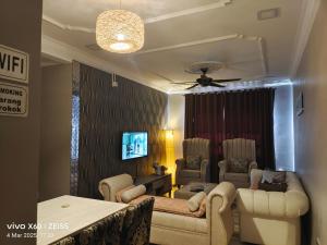 a living room with a couch and chairs and a tv at Penginapan Puncak 28 in Kuala Terengganu