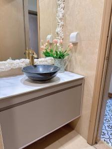 a bathroom counter with a sink and a vase of flowers at Luxury Apartment in Vinhomes Times City - KaBi Home in Hanoi