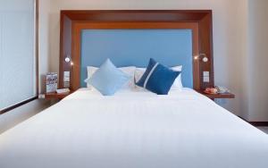 a bedroom with a large white bed with blue pillows at Novotel Atlantis Shanghai - Enjoy our great-valued breakfast in our rooftop revolving restaurant with a stunning river view & utilize our FREE self-serviced laundry in Shanghai
