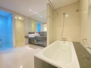 a bathroom with a large white tub and a sink at Fabulous 2BR Loft Apartment with Private Bathub at El Royale By Travelio in Bandung