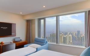 a room with a bed and a chair and a large window at Novotel Atlantis Shanghai - Enjoy our great-valued breakfast in our rooftop revolving restaurant with a stunning river view & utilize our FREE self-serviced laundry in Shanghai