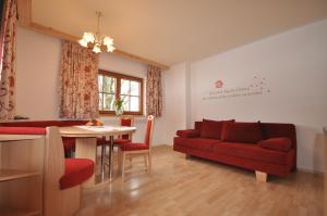 a living room with a red couch and a table at Activ Wellness - Appartement Schermerhof in Westendorf