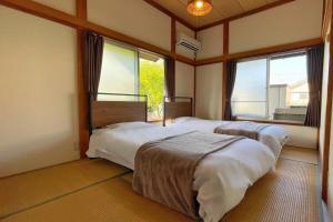 Dos camas en una habitación con dos ventanas. en 古民家美ら 鴨川, en Kamogawa 11 fotos más