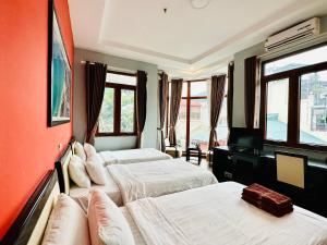 una camera d'albergo con tre letti e finestre di Hanoi Buffalo Hostel a Hanoi