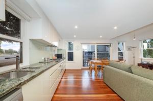 Una cocina y una sala de estar con un sofá y una mesa. en Johanssons Perch Cottage, en Port Fairy