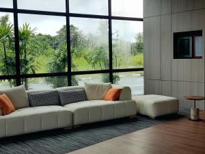 a living room with a white couch and a large window at Roxy Hotel Malihah in Kampong Sungai Tengah