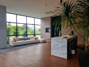 a living room with a white couch and a palm tree at Roxy Hotel Malihah in Kampong Sungai Tengah
