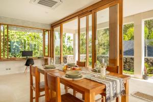 a dining room with a table and chairs and windows at Villa Damai Rohani Private Pool Villas with Valley Views Adults Only in Sidemen