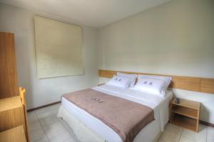 a bedroom with a large white bed with white pillows at Hotel Pedra da Concha in Salvador