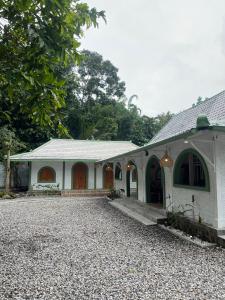 a white house with a gravel driveway in front of it at Sampai Villa nDalem Kaliurang in Cangkringan