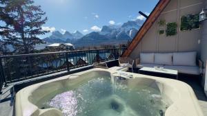 a hot tub on a balcony with a view of mountains at Memory Lodge in Canmore