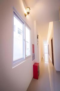 a white hallway with a window and a red box at 1991 Hotel in Phan Thiet +39 photos