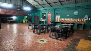a dining room with tables and chairs and green walls at Hill Valley Farm House in Nelliyampathy