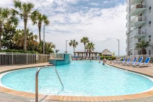 a swimming pool at a resort with chairs and palm trees at Seaside Serenity - Destin, FL in Destin