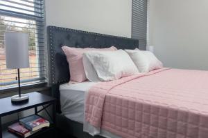 a bedroom with a bed with pink and white pillows at New Cougar Cabin with Air Hockey in Purcell