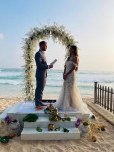 a bride and groom standing under an arch on the beach at Luxury 3-BR Beach Front Villa with Staff in Habaraduwa +84 photos