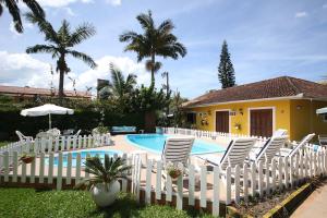 a group of white chairs and a swimming pool at Pousada Jardim Porto Belo in Porto Belo