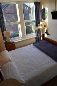 a bedroom with a large bed with two windows at The Avenue Bed and Breakfast in Newcastle upon Tyne
