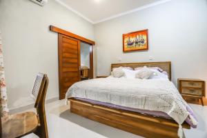 a bedroom with a bed and a chair and a window at Unwind in 2BDR Ubud Villa Oceania - Huge Pool & Lawn in Ubud